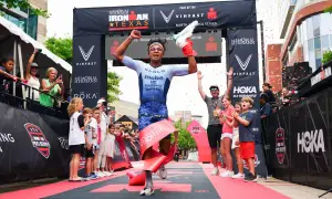 A triumphant athlete breaks the tape at the Memorial Hermann Ironman Texas, celebrating a victory in this demanding team triathlon event.