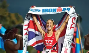Chrissie Wellington celebrates her Ironman World Championship win, draped in the Union Jack and holding the Ford Ironman banner.