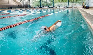 A woman enjoys a 30-minute pool workout, swimming laps in a bright blue lane.