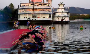 Triathletes dive into the water at 70.3 Chattanooga, with paddle boats and riverboats in the background.