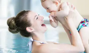 Mother and baby laughing in a pool. A happy mom asks, "When can you swim after C-section?