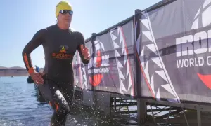 Athlete emerges from water, ready for the full Ironman distance. A banner reads "Ironman World Championship.