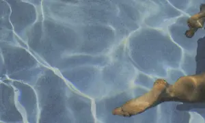 Sunlight dances on the water's surface, illuminating submerged feet. Does chlorine kill yeast on skin? This pool might offer an answer.
