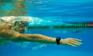 Underwater view of a swimmer in goggles and cap, focused on a long distance swim, with a smartwatch on their wrist tracking progress.