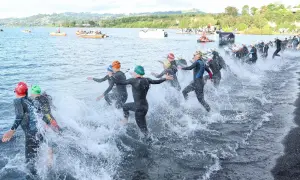 Triathletes charge into the water, kicking up spray as they begin the swim portion of a boulder half ironman race.