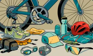 Ready for a triathlon! Cycling shoes, goggles, a helmet, sunglasses, and a water bottle are laid out with a bike.