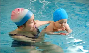 A mother and baby in a pool. It's never too early to consider when to start baby swim lessons for water safety and fun.