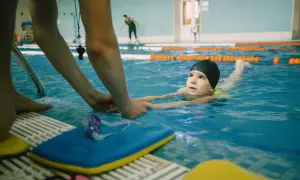 A child learns to swim with an instructor's help, experiencing the benefits of water safety and physical activity.