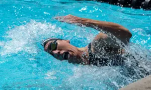 Swimmer in goggles and cap powers through the water, mid-stroke, preparing for a flip turn.