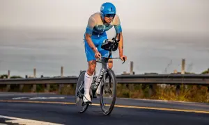A determined triathlete, perhaps a beginner, races on a bike, focused on the road ahead.