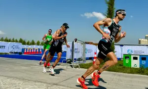 Triathletes push hard on the run course, a key part of their sprint tri training plan. Bright sun, blue skies, and a competitive spirit.