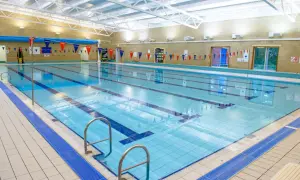 An empty indoor swimming pool with lanes marked, ready for an adult swim school class.