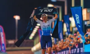 India Lee celebrates a victory, holding up a "Miami T100 World Tour" banner.