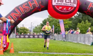 A woman crosses the finish line at a triathlon, smiling. This event is one of the best triathlons for participants to achieve their goals.