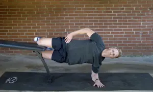 Man performing a side plank on a bench, a key exercise for core workouts for swimmers.