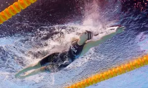 Katie Ledecky training underwater, powering through the water in a USA swimsuit.