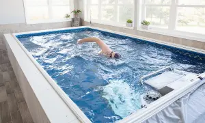 Man swims laps in a compact triathlon pool, enjoying an endless swim against a gentle current.