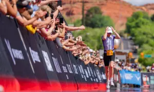 Athlete 53 runs towards the finish line at Ironman 70.3 St. George, greeted by a cheering crowd.
