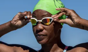 A swimmer adjusts her goggles, ready to dive in. She's proving you can swim with a burn, embracing the water.