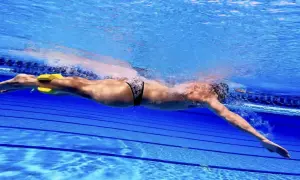 Swimmer using a pull buoy between legs to isolate arm stroke. This technique helps improve upper body strength and efficiency, demonstrating how to use a pull buoy effectively.