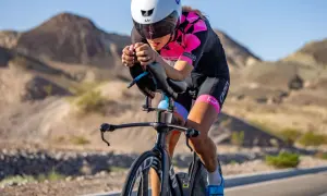 A determined woman competes in a womens triathlon, cycling intensely through a desert landscape.