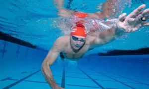 Underwater view of a swimmer performing a freestyle swim stroke, with arms extended and water splashing around.