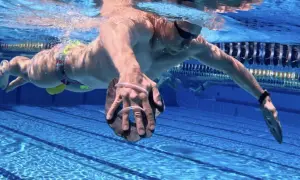 Swimmer performing a paddle drill, using hand paddles to increase resistance and build strength in the water.