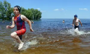 Young athletes splash through the water during a youth triathlon.