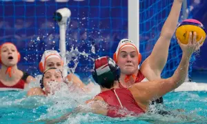 Intense water polo action, with players battling for the ball. The struggle suggests potential water polo fouls as they jostle for position near the goal.