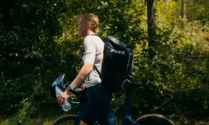 Athlete walks with bike and gear, preparing for the next stage in triathlon transition areas.