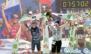 Two athletes celebrate crossing the finish line, one holding a bouquet, achieving their fastest Ironman time.