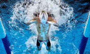 Swimmer powering through intense swim practice sets, creating a splash as they break the water's surface.