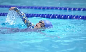 A young swimmer practices the side stroke, their arm slicing through the water.