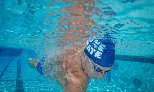 Underwater view of a swimmer's powerful swimmer lats as they glide through the blue water, bubbles trailing behind.