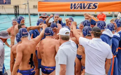 Waterpolo development: A team huddles, fists raised, showing unity and focus before a game.