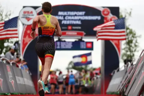 A triathlete runs towards the finish line at the USA Triathlon Multisport National Championships Festival, a testament to their USA Triathlon membership.