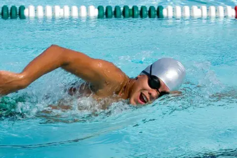 Swimmer in a pool, focused on endurance workouts, powering through the water with determined strokes.