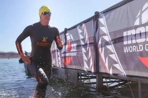 Athlete emerges from water, ready for the full Ironman distance. A banner reads "Ironman World Championship.
