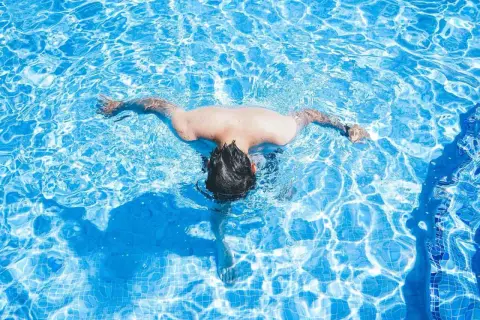 A person swims in a bright blue pool. Wondering how often should I swim? This refreshing activity is great for fitness.
