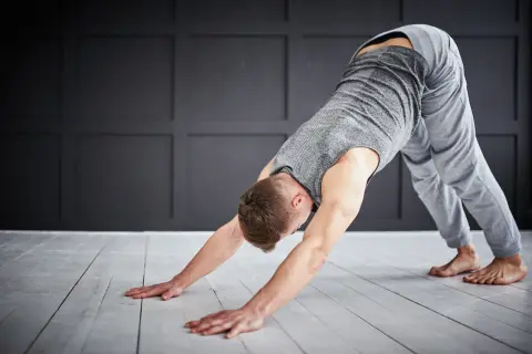 Man in downward-facing dog pose, a key stretch for yoga for triathletes, improving flexibility and recovery.