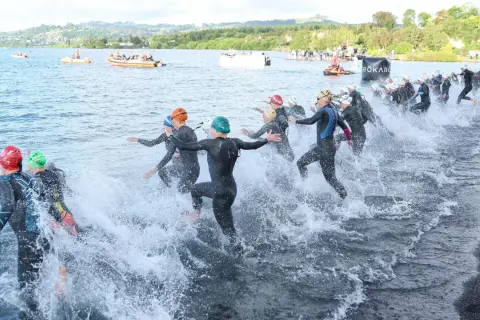 Triathletes charge into the water, kicking up spray as they begin the swim portion of a boulder half ironman race.