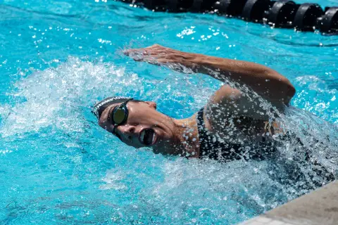 Swimmer in goggles and cap powers through the water, mid-stroke, preparing for a flip turn.