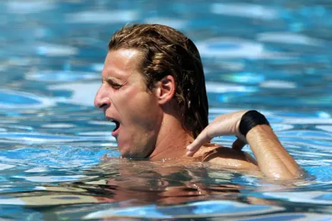 A swimmer gasps for air, his arm reaching back. The resistance of the water explains why does the pool make you tired.