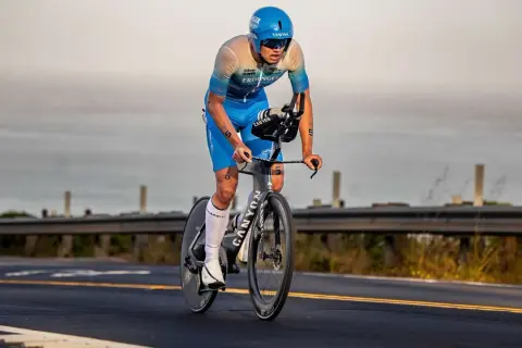 A determined triathlete, perhaps a beginner, races on a bike, focused on the road ahead.