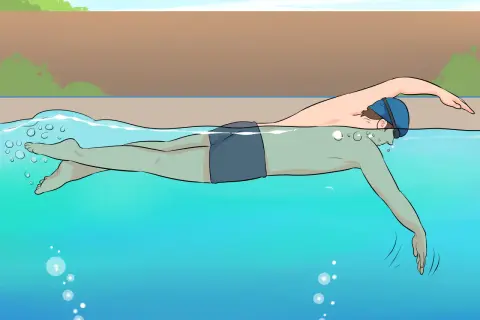 A person in swim cap and goggles practices freestyle swimming, a common stroke for beginner swim lessons for adults.