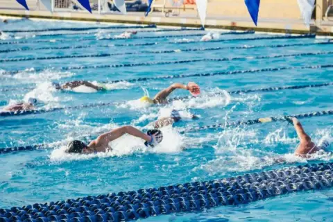 Swimmers push through the water in a competitive race, showcasing an intense hiit swim workout.