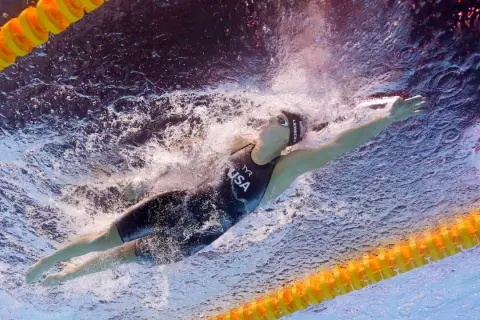 Katie Ledecky training underwater, powering through the water in a USA swimsuit.