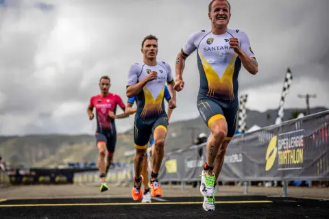 Triathletes race, pushing their limits. The lead runner's determined face hints at the grueling Ironman triathlon distances ahead.
