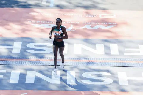 Runner crosses the finish line in her Under Armour tri suit, a testament to her endurance and dedication.