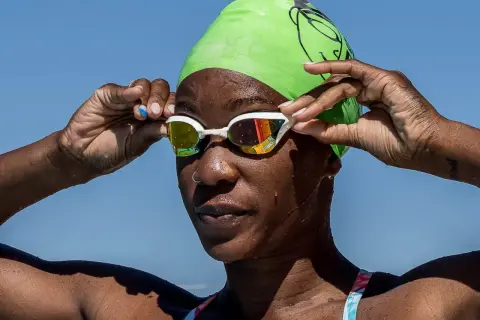 A swimmer adjusts her goggles, ready to dive in. She's proving you can swim with a burn, embracing the water.